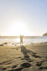 Mann steht bei Sonnenuntergang am Strand und fotografiert, Insel Sao Miguel, Azoren, Portugal - AFVF05704