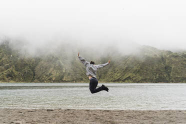 Ein Mann springt in voller Länge in die Luft, während er seinen Urlaub auf der Insel Sao Miguel, Azoren, Portugal, genießt - AFVF05715