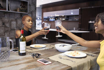 Zwei Freunde, die zu Hause gemeinsam zu Abend essen und mit Rotwein anstoßen - VEGF01710