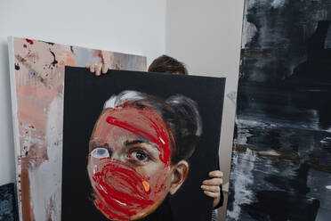 Eine Malerin versteckt sich hinter einem Bild in ihrem Atelier - OGF00235