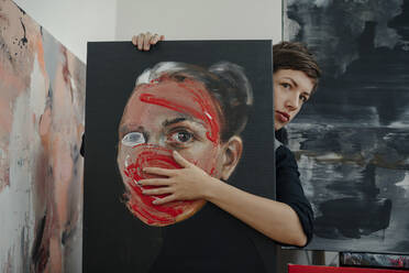 Porträt einer Malerin mit Gemälde in ihrem Atelier - OGF00237