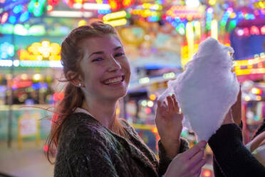 Porträt eines glücklichen rothaarigen Teenagers mit Zuckerwatte auf dem Oktoberfest - LBF02951