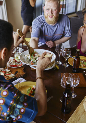 High angle view of multi-ethnic friends eating lunch while sitting at dining table stock photo