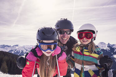 Glücklicher Vater umarmt seine Töchter beim Skiurlaub am Spitzingsee, Bayern, Deutschland - DHEF00156