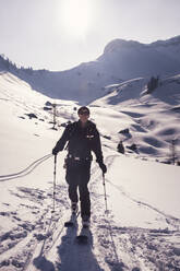 Mann in voller Länge beim Skifahren auf einem verschneiten Berg in Achenkirch, Tirol, Österreich, an einem sonnigen Tag - DHEF00161