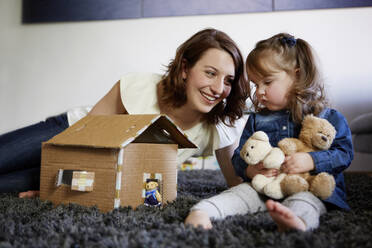 Glückliche junge Mutter, die mit ihrer kleinen Tochter zu Hause spielt - AUF00143