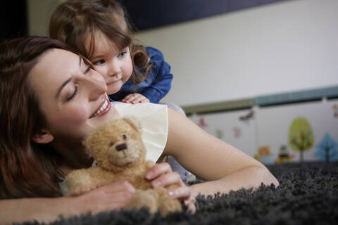 Portrait of toddler girl cuddling with her mother at home stock photo