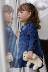 Portrait of curios toddler girl with teddy bear watching something - AUF00158