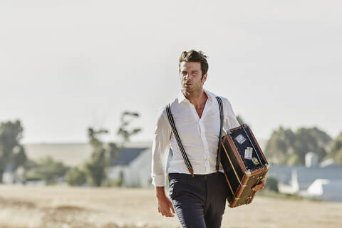 Man in old-fashioned clothes with suitcase in the countryside stock photo