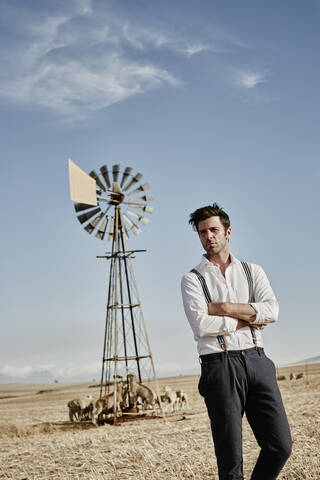 Man in old-fashioned clothes with flock of sheep in the countryside stock photo