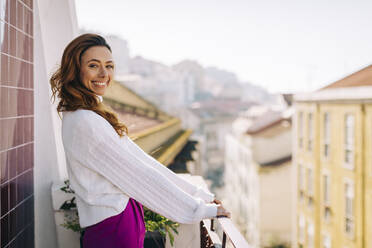 Portrait of happy young woman standing on balcony - DCRF00175