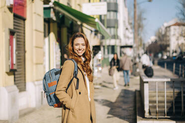 Portrait of happy young woman with backpack in the city, Lisbon, Portugal - DCRF00178