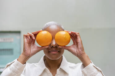 Frau bedeckt ihre Augen mit Orangen im Freien - AFVF05742