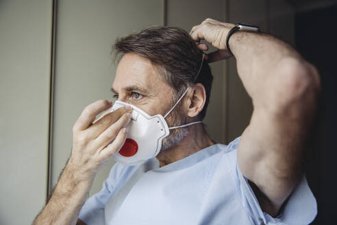 Male health worker putting on FFP3 mask - MFF05073