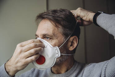 Mature man putting on protective mask - MFF05078