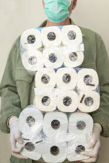 Man with face mask and protective gloves, holding packets of toilet paper - AFVF05769