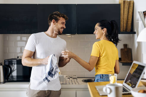 Glückliches junges Paar beim gemeinsamen Abwaschen in der Küche zu Hause - SODF00706