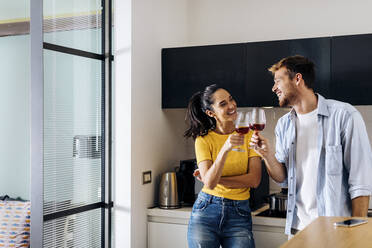 Happy young couple drinking wine in the kitchen at home together - SODF00709