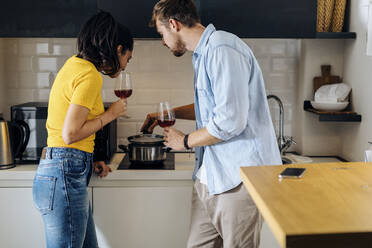 Junges Paar kocht und trinkt Wein in der Küche zu Hause zusammen - SODF00711