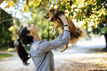 Glückliche junge Frau mit Hund in einem Park - SODF00716