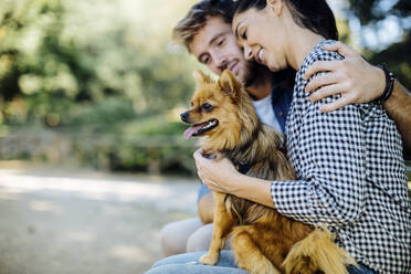 Glückliches junges Paar mit Hund in einem Park - SODF00725