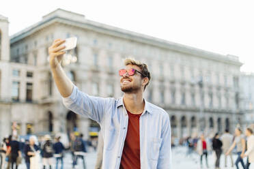 Lächelnder junger Mann macht ein Selfie in der Stadt, Mailand, Italien - SODF00736