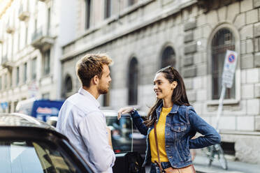 Young couple talking at a car in the city, Milan, Italy - SODF00739