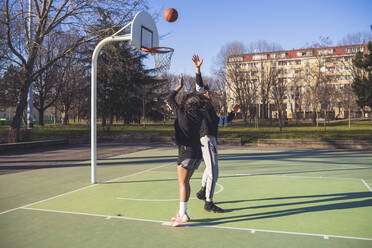 Junger Mann und Frau spielen Basketball auf dem Platz - MEUF00055