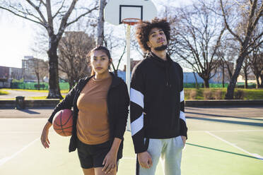 Porträt eines jungen Mannes und einer Frau, die auf einem Basketballplatz stehen - MEUF00060