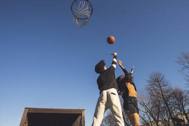 Junger Mann und Frau spielen Basketball auf dem Platz - MEUF00070