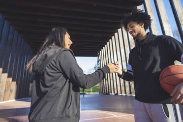 Young man and woman meeting on basketball court - MEUF00073