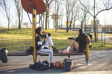 Sportliches junges Paar, das auf einer Bank sitzend eine Pause einlegt - MEUF00081