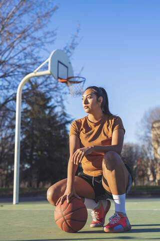 Basketballspielerin hockt auf dem Platz, lizenzfreies Stockfoto