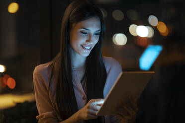 Porträt einer lächelnden jungen Frau, die ein digitales Tablet im Büro benutzt - JSRF00942