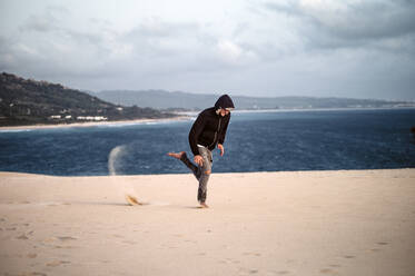 Young man jumping at beach against sky in Tarifa, Spain - OCMF01061