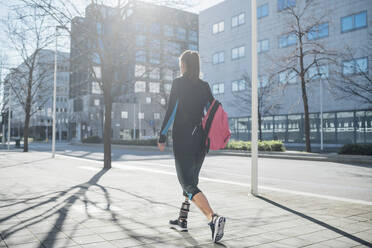 Sportliche junge Frau mit Beinprothese beim Spaziergang in der Stadt - MEUF00110