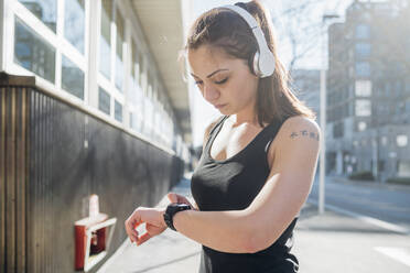 Sporty young woman using smartwatch in the city - MEUF00119