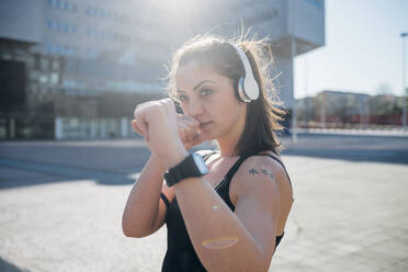 Portrait of confident sporty young woman with headphones in the city - MEUF00126