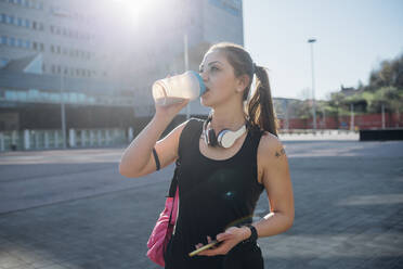 Sporty young woman drinking from cup in the city - MEUF00135