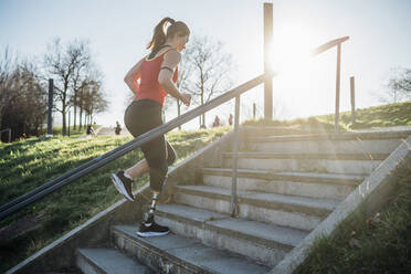 Sporty young woman with leg prosthesis running up stairs - MEUF00144