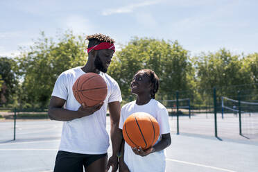 Vater und Sohn mit Basketball auf dem Basketballplatz - JPIF00502
