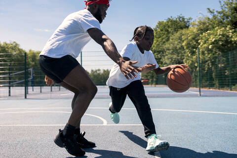 Father and son playing basketball on basketball court stock photo