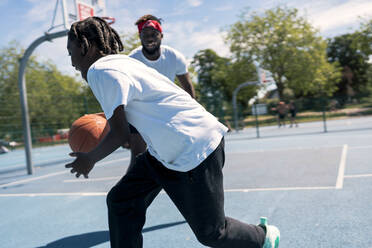 Father and son playing basketball on basketball court - JPIF00512
