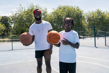Father and son with basketball on basketball court - JPIF00514