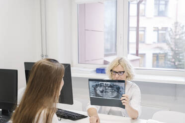 Zahnarzt spricht mit dem Patienten über die Röntgenergebnisse - AHSF02027
