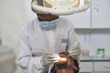 Female dentist cleaning teeth of a man - VEGF01786