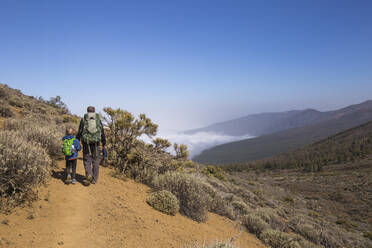 Rear view of a father with his son trekking in the Arenas Negras area, Teide National Park, Tenerife - IHF00289