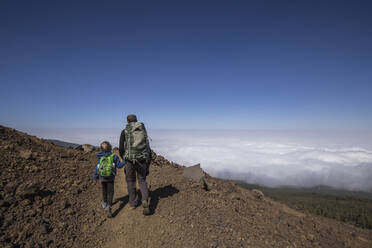 Rear view of a father with his son trekking in the Arenas Negras area, Teide National Park, Tenerife - IHF00290