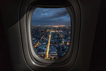 Beleuchtete Stadtlandschaft durch Flugzeugfenster bei Nacht gesehen - EYF01059