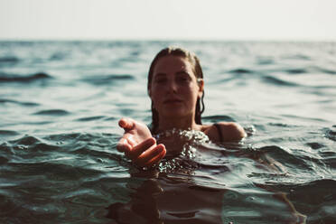 Porträt einer Frau, die beim Schwimmen im Meer gestikuliert - EYF01192